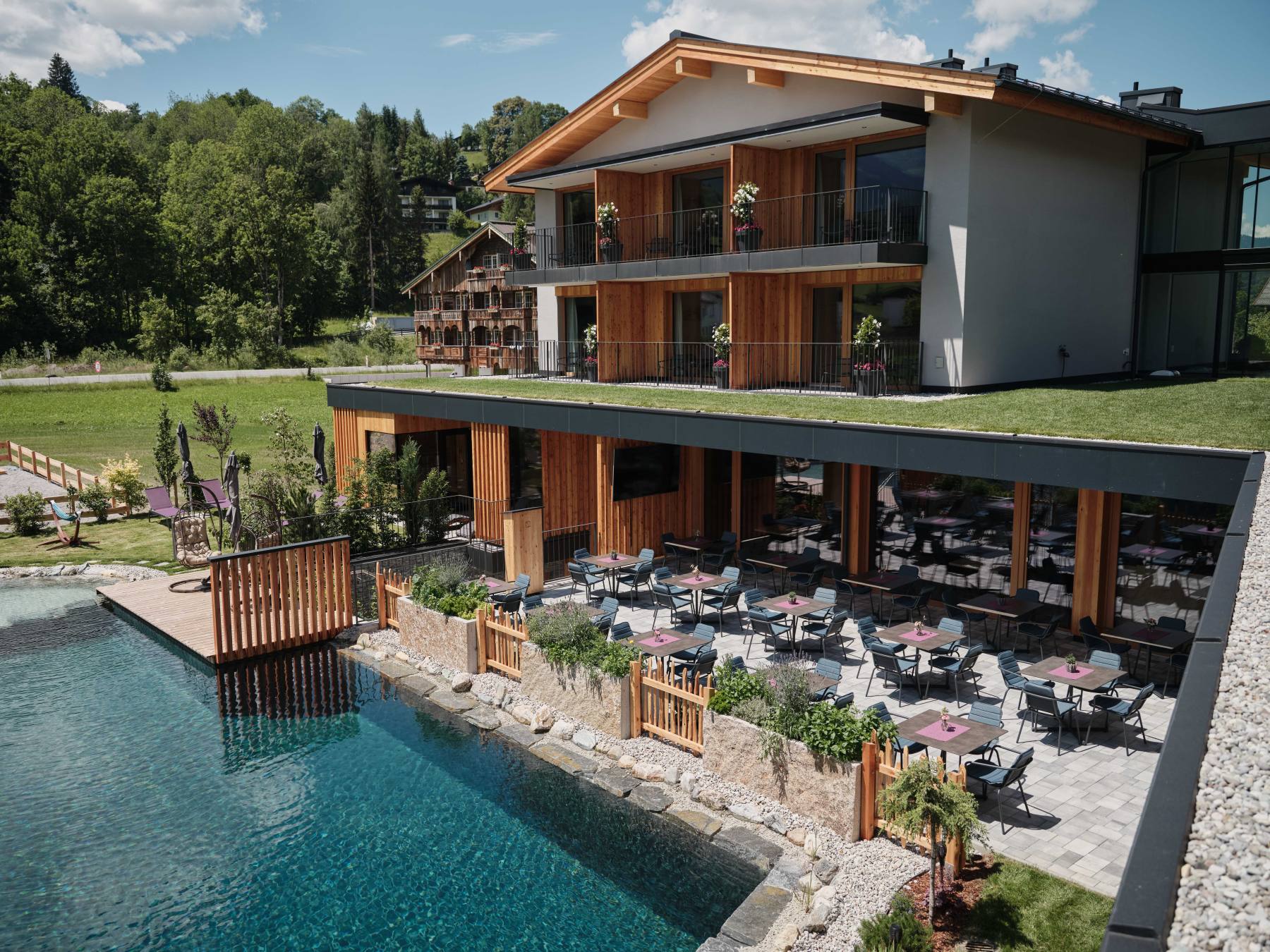 Aussenansicht des Hotels mit Blick auf den Naturpool und der Sonnenterrasse
